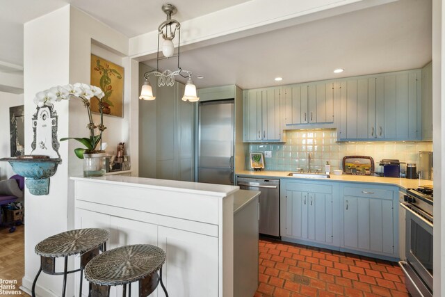 kitchen featuring appliances with stainless steel finishes, pendant lighting, sink, decorative backsplash, and kitchen peninsula