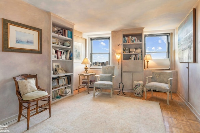 living area featuring built in shelves, plenty of natural light, and light parquet flooring