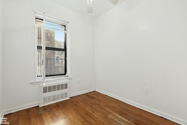 unfurnished room featuring hardwood / wood-style flooring, ceiling fan, baseboards, and radiator heating unit
