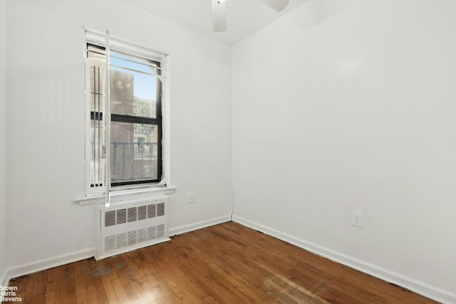 empty room featuring a ceiling fan, radiator, baseboards, and dark wood-style flooring