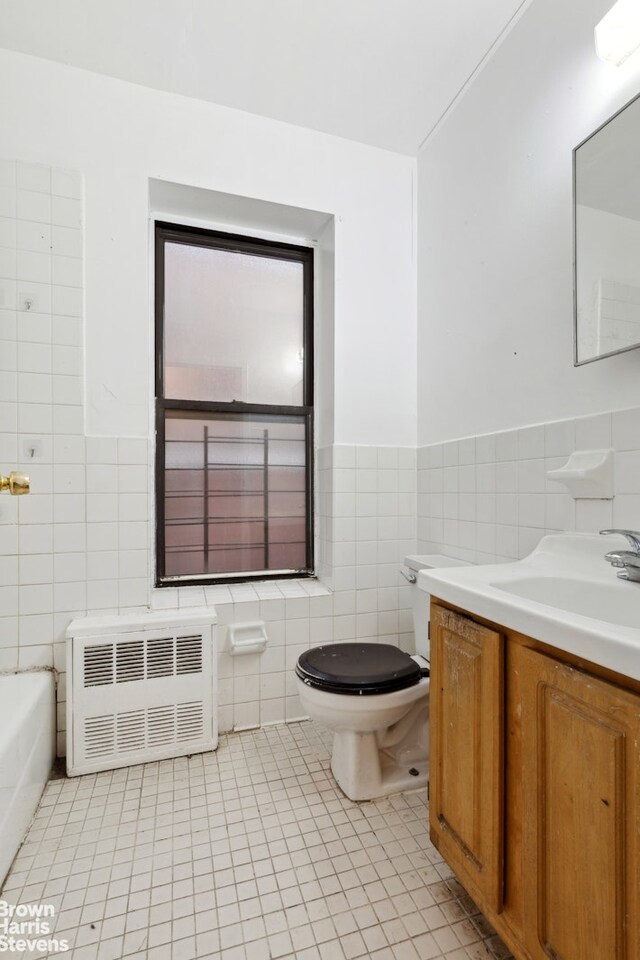 bathroom featuring radiator, tile patterned flooring, vanity, tile walls, and toilet