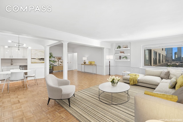 living area featuring decorative columns and crown molding