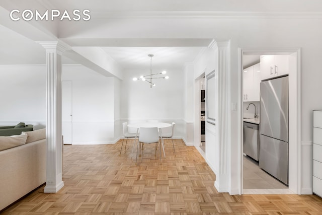 45 Sutton Pl S Unit 15G, New York City, NY 10022 - kitchen with stainless steel appliances, white cabinetry, a chandelier, crown molding, and hanging light fixtures