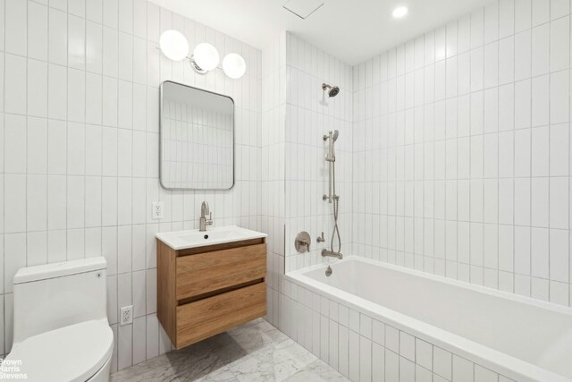 full bathroom with tile walls, tiled shower / bath combo, vanity, and toilet