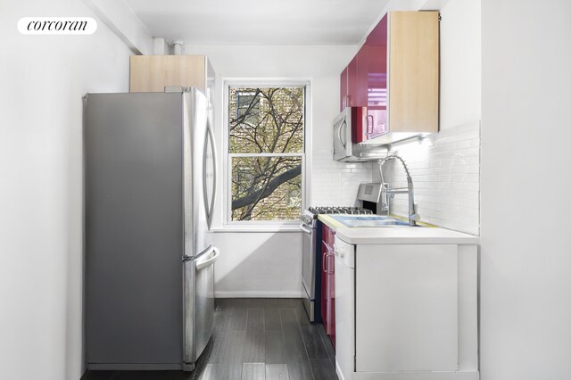 kitchen with tasteful backsplash, appliances with stainless steel finishes, plenty of natural light, and dark hardwood / wood-style flooring