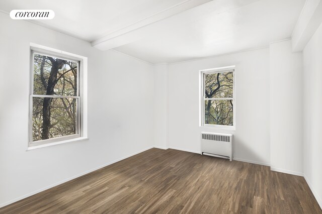 spare room featuring a healthy amount of sunlight, dark hardwood / wood-style floors, radiator, and beam ceiling