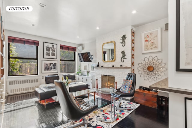 office space featuring wood-type flooring, a brick fireplace, plenty of natural light, and radiator heating unit