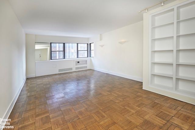 unfurnished living room with dark parquet floors and built in shelves