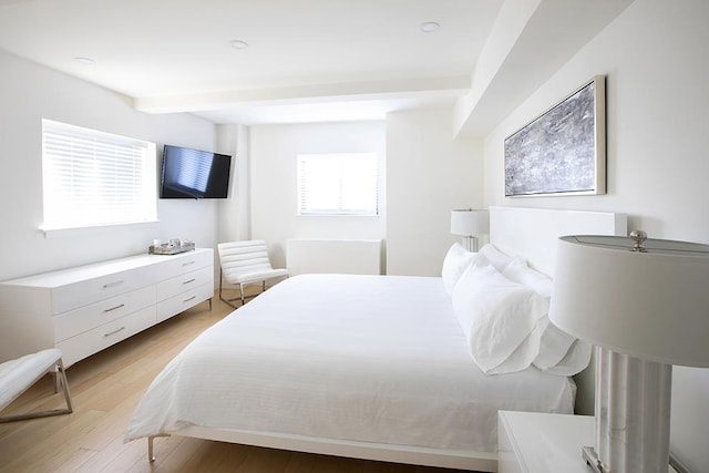 bedroom with beam ceiling and light wood-type flooring