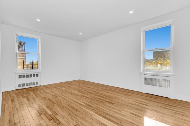 empty room with radiator, a healthy amount of sunlight, and light hardwood / wood-style flooring