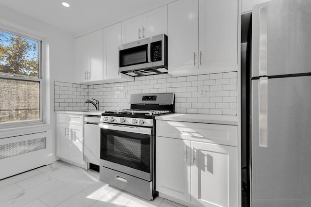 kitchen featuring white cabinets, decorative backsplash, appliances with stainless steel finishes, and sink