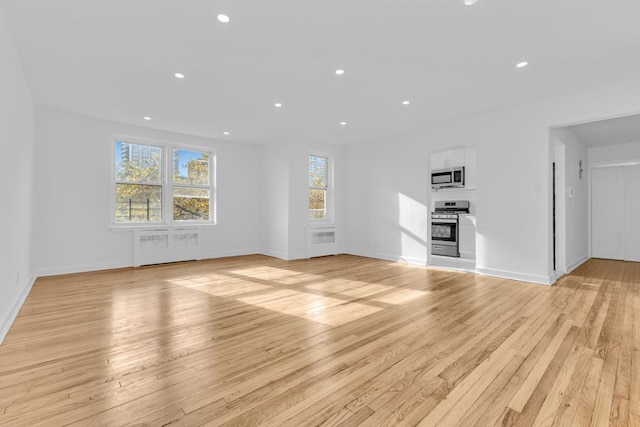 unfurnished living room with radiator heating unit and light hardwood / wood-style flooring