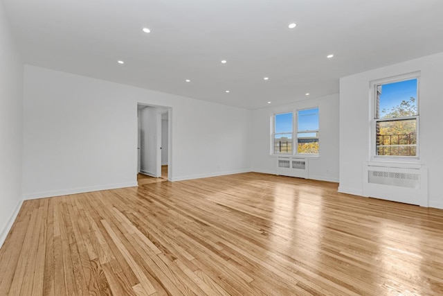 unfurnished room with radiator and light wood-type flooring