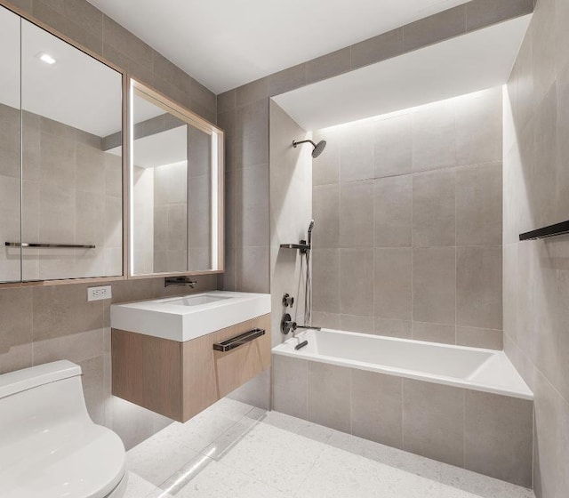 full bathroom featuring tile walls, toilet, vanity, and tiled shower / bath