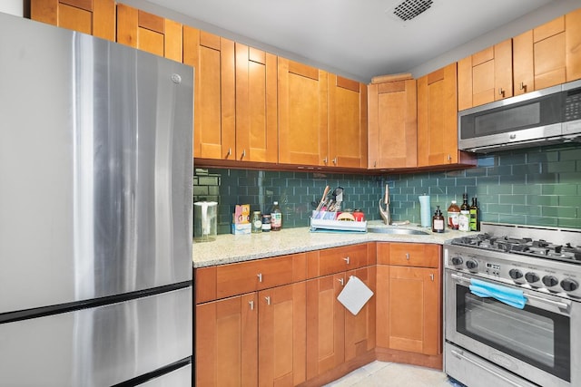 kitchen featuring light stone countertops, light tile patterned floors, sink, backsplash, and stainless steel appliances