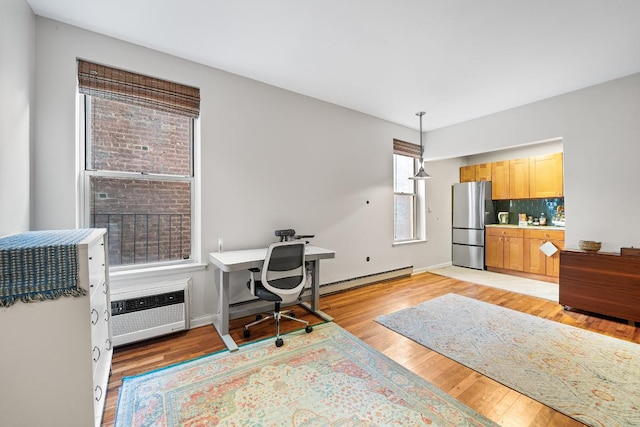 office featuring light hardwood / wood-style flooring, a baseboard heating unit, and a wealth of natural light