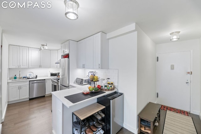 kitchen with decorative backsplash, kitchen peninsula, white cabinetry, and stainless steel appliances