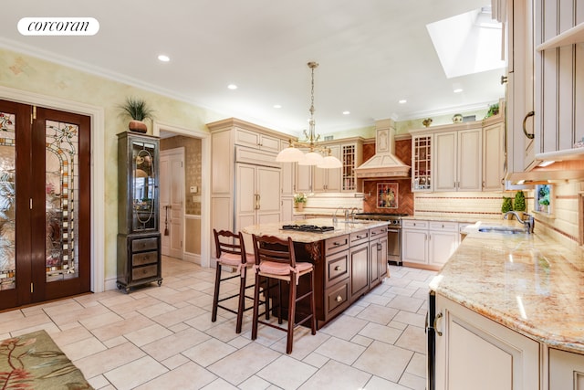 kitchen featuring high end stove, custom range hood, visible vents, and cream cabinetry