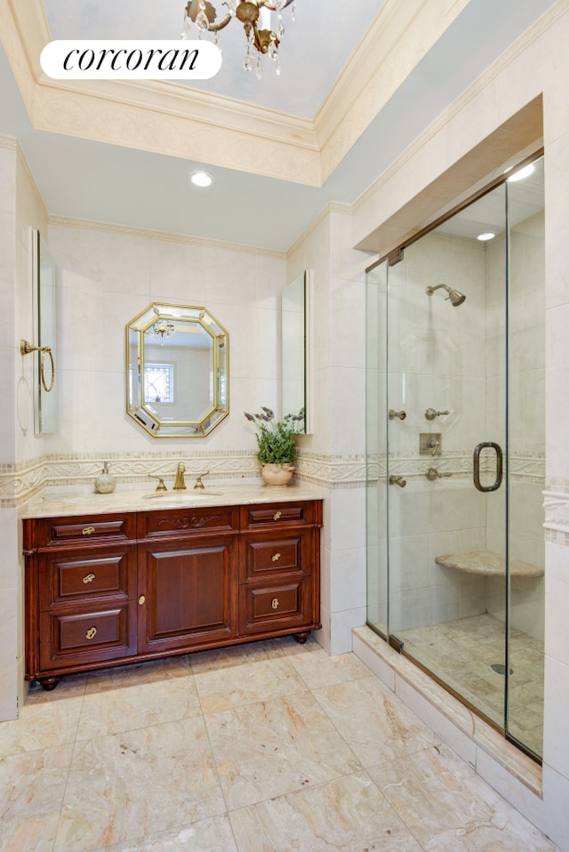 full bathroom with vanity, tile walls, ornamental molding, a shower stall, and a raised ceiling