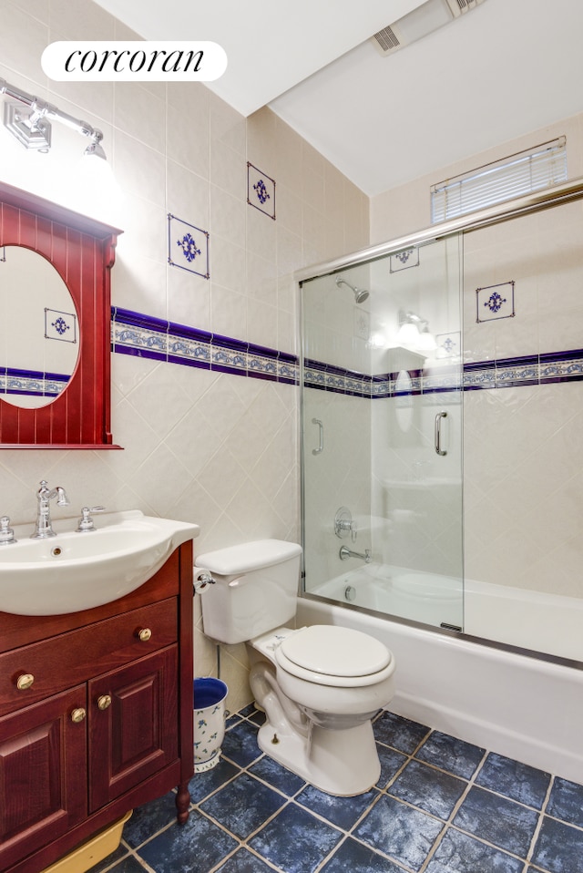 bathroom with tile walls, toilet, enclosed tub / shower combo, vanity, and tile patterned floors