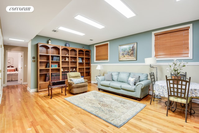 living area with visible vents, baseboards, and wood finished floors