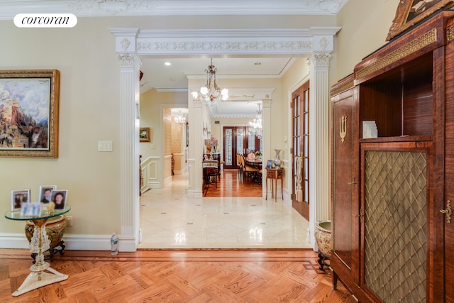 hallway featuring decorative columns, visible vents, baseboards, ornamental molding, and a chandelier