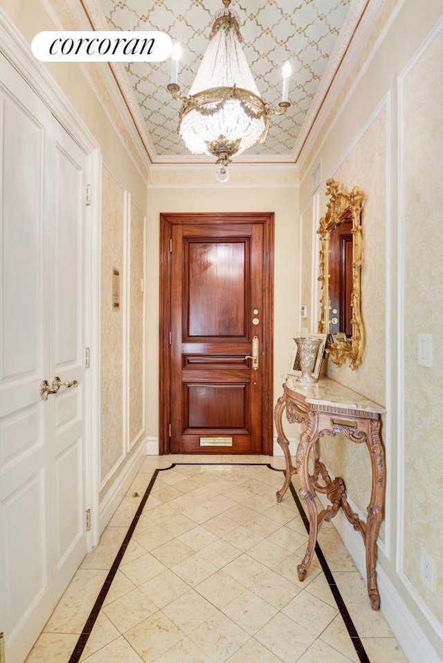 doorway featuring an inviting chandelier, baseboards, visible vents, and ornamental molding