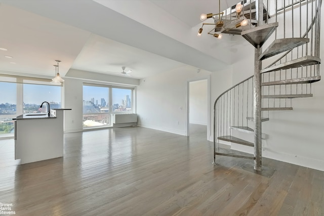 446 Kent Ave Phd, Phd, New York City, NY 11211 - unfurnished living room with a view of skyline, wood finished floors, stairway, and baseboards