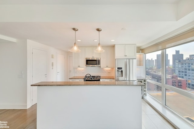 kitchen with tasteful backsplash, stone countertops, white cabinets, appliances with stainless steel finishes, and a view of city