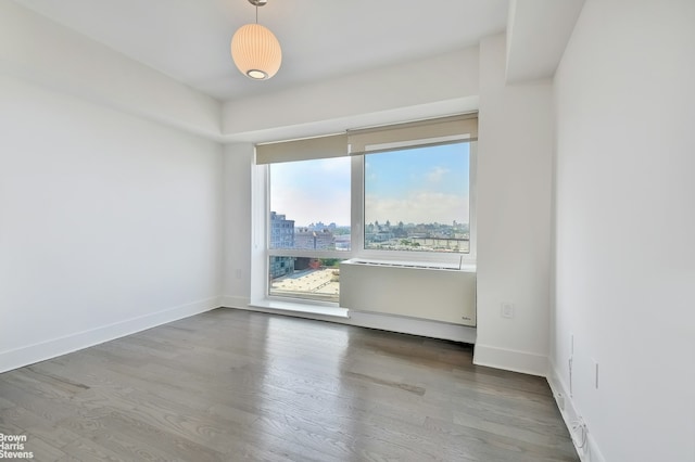 unfurnished room with a view of city, wood finished floors, and baseboards