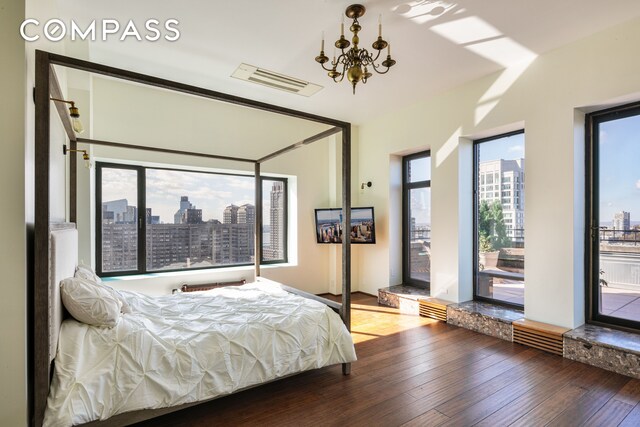 bedroom with a notable chandelier, hardwood / wood-style flooring, visible vents, and access to exterior