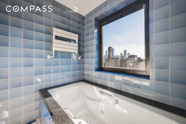 bathroom with a view of city, radiator heating unit, tile walls, and a whirlpool tub