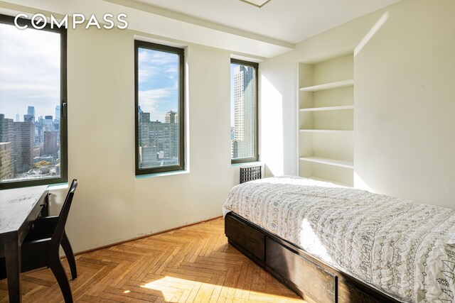 bedroom featuring multiple windows and a city view