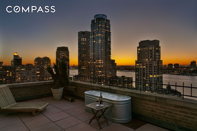 patio terrace at dusk with a view of city and a water view