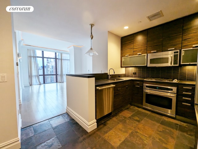 kitchen with sink, tasteful backsplash, kitchen peninsula, pendant lighting, and stainless steel appliances