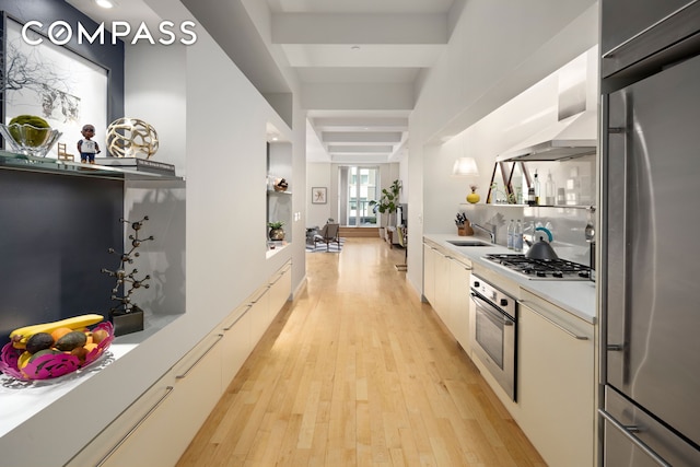 kitchen with extractor fan, light countertops, light wood-style flooring, stainless steel appliances, and a sink