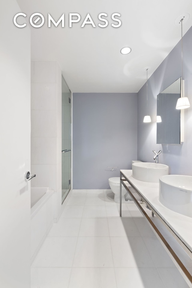 bathroom with tile patterned floors, toilet, a sink, a shower stall, and a bath