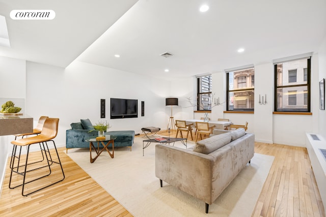 living room with light wood-type flooring, visible vents, and recessed lighting