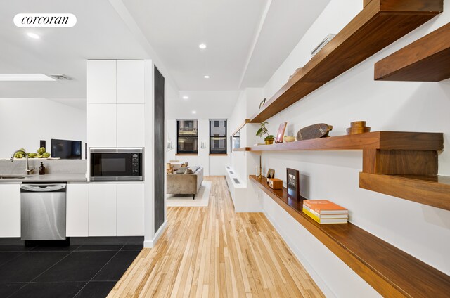 176 Broadway Unit 3C, New York City, NY 10038 - kitchen featuring dishwasher, built in microwave, modern cabinets, white cabinetry, and open shelves