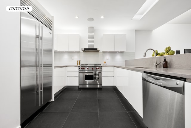 kitchen featuring premium appliances, a sink, white cabinetry, wall chimney exhaust hood, and modern cabinets