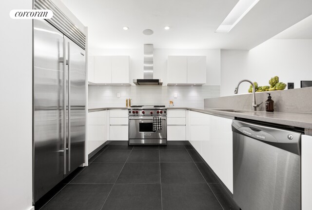 176 Broadway Unit 3C, New York City, NY 10038 - kitchen with premium appliances, modern cabinets, wall chimney range hood, a sink, and white cabinetry