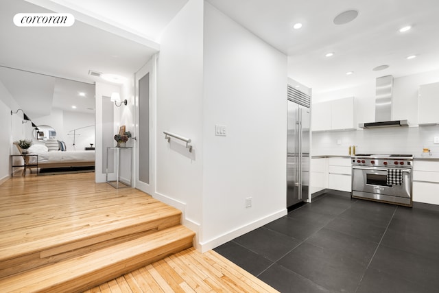 interior space with premium appliances, visible vents, white cabinetry, wall chimney exhaust hood, and modern cabinets