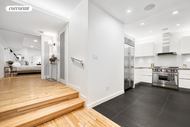 176 Broadway Unit 3C, New York City, NY 10038 - kitchen with high end appliances, wall chimney range hood, white cabinets, modern cabinets, and light countertops