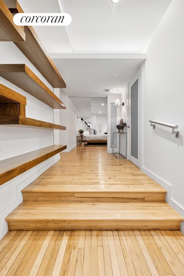 stairs with hardwood / wood-style floors, visible vents, and baseboards