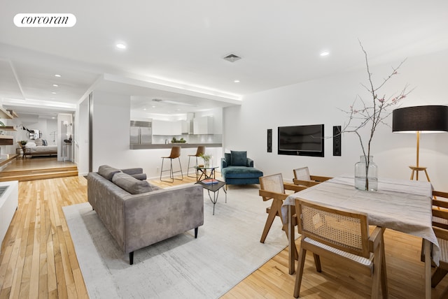 living room with recessed lighting, visible vents, and light wood finished floors