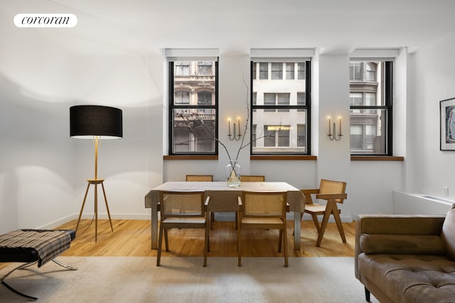 dining space with wood finished floors, visible vents, and baseboards