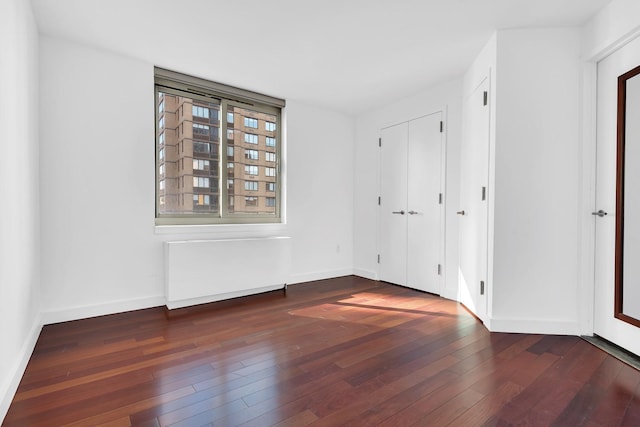 unfurnished bedroom featuring baseboards and dark wood-type flooring