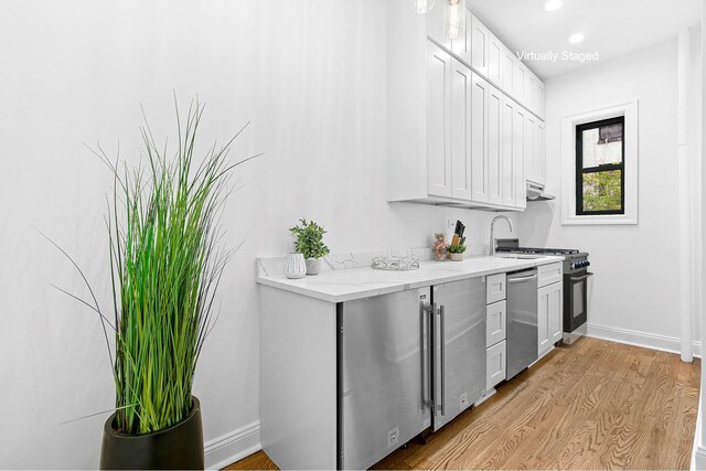 kitchen with light stone counters, white cabinetry, baseboards, dishwasher, and light wood finished floors