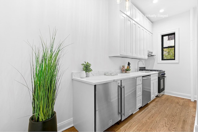 104 E 37th St Unit 3F, New York City, NY 10016 - kitchen featuring dishwasher, light wood-style flooring, baseboards, light stone counters, and white cabinetry