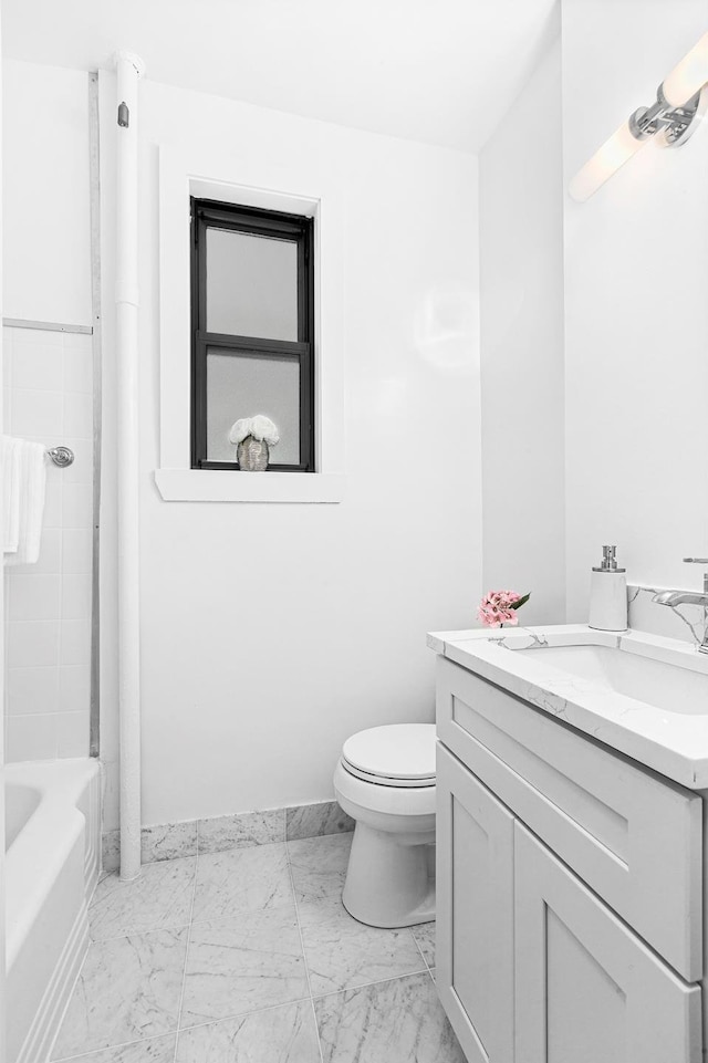 bathroom featuring toilet, marble finish floor, vanity, and baseboards